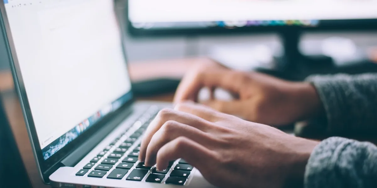 Mãos digitando em um notebook para consulta das contribuições